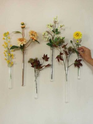 voorbeeld van deze buisjes gevuld met bloemen en opgehangen tegen een muur